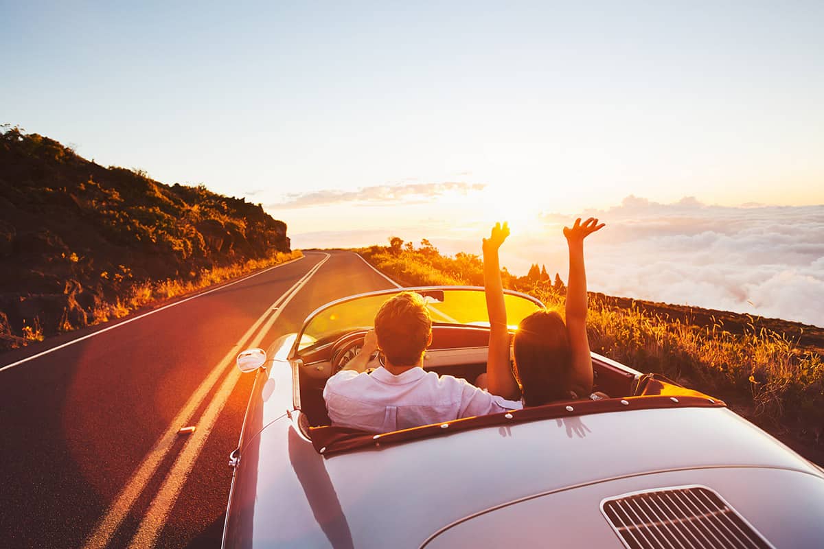 Happy,Couple,Driving,On,Country,Road,Into,The,Sunset,In